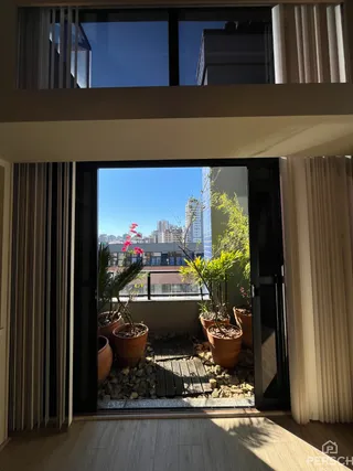 Vista de um terraço com plantas e paisagem urbana.