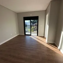 Sala com piso de madeira e portas de vidro que dão acesso ao exterior.