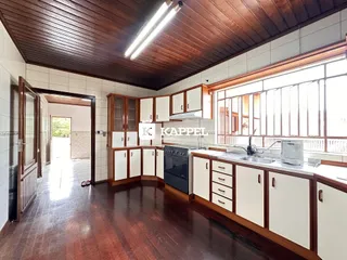 Esta é uma foto da cozinha com armários brancos e piso de madeira.
