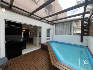 Vista de uma área externa com piscina e deck de madeira em uma residência.