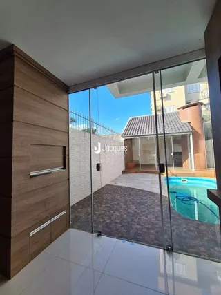 Vista interna de uma sala de estar com portas de vidro que dão acesso a uma área externa.