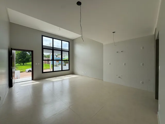 Sala ampla com grandes janelas e piso claro.