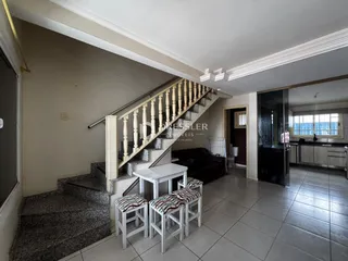 Ambiente interno com escadaria e mesa de centro em um imóvel.