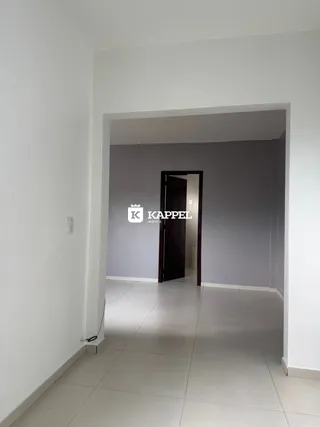 Uma foto de um corredor interno com paredes brancas e piso claro.