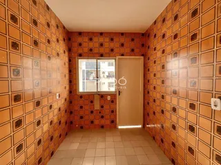 Corredor com revestimento de azulejos terracota nas paredes.