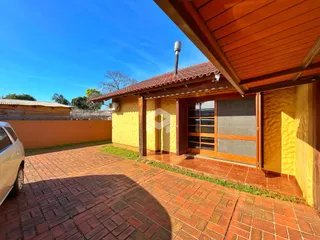 Fachada de uma casa com parede amarela e piso de tijolos vermelhos no exterior.