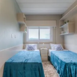 Quarto com cama azul e prateleiras de parede em um imóvel.