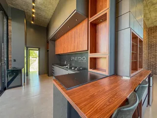 Vista da cozinha moderna com armários de madeira e bancadas escuras.