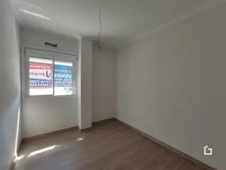 Interior de um cômodo com piso de madeira clara e paredes brancas.