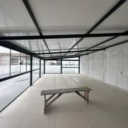 Foto de um espaço interno com piso claro e estrutura de teto exposta.