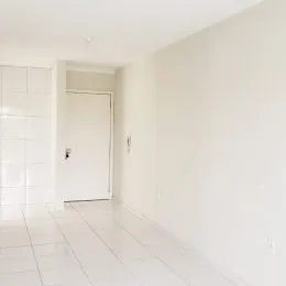 Corredor interno com piso de cerâmica branca e paredes brancas.