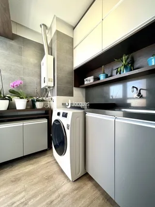 Vista da cozinha moderna com armários brancos e bancadas claras.