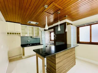 Cozinha com teto de madeira e armários brancos em um ambiente moderno.