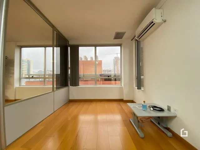 Interior de um ambiente com piso de madeira e janela grande.