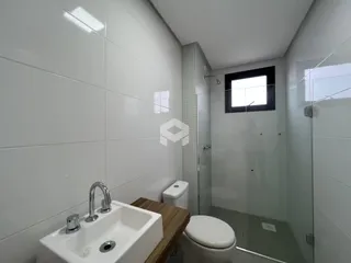 Banheiro com revestimento cerâmico e box de vidro.