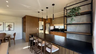 Cozinha moderna com ilha escura e área de jantar adjacente.