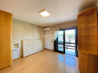 Quarto com cabeceira estofada e piso de madeira clara.