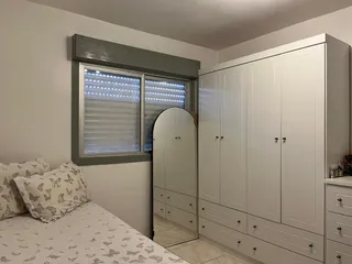 Foto de um quarto com cama e armário branco.