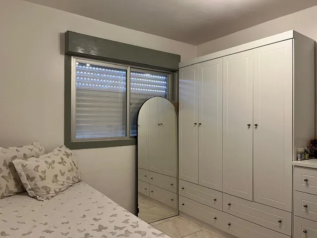 Foto de um quarto com cama e armário branco.