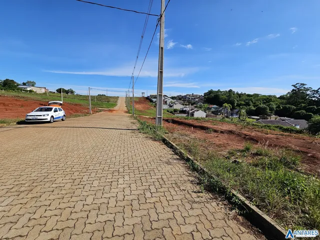 Uma estrada pavimentada leva a uma área rural com casas ao fundo.