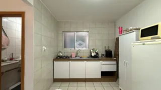 Interior da cozinha com revestimento de azulejos brancos e armários brancos.