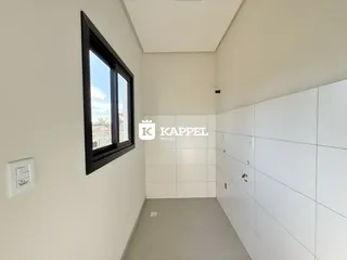 Hall de corredor com paredes brancas e uma janela na lateral.