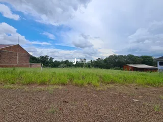 Campo de grama verde com construções rurais ao fundo.