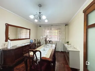 Uma sala de jantar com móveis de madeira e cortinas.