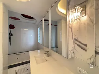 Banheiro com revestimento branco e bancada de mármore.