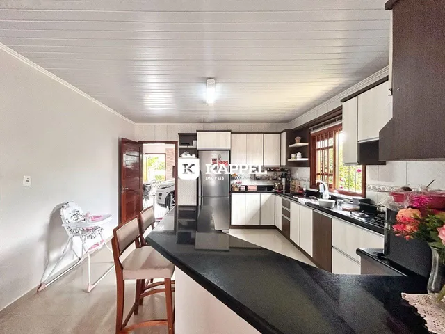 Cozinha moderna com armários brancos e bancada escura.