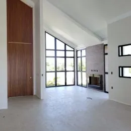 Sala ampla com pé direito alto e grandes janelas que dão vista para o exterior.