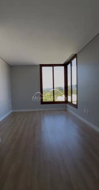 Sala de estar com piso de madeira e grande janela voltada para a paisagem.