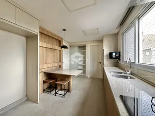Vista interna de uma cozinha moderna com armários de madeira e bancada clara.