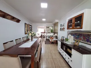 Foto de um ambiente interno com mesa de jantar de madeira e armários na cozinha.