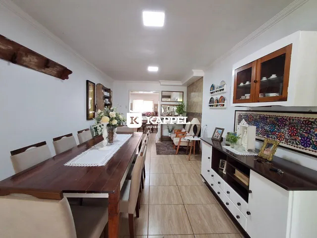 Foto de um ambiente interno com mesa de jantar de madeira e armários na cozinha.