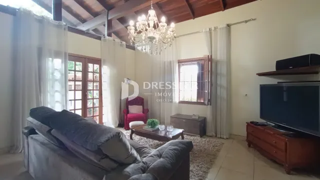 Sala de estar com grandes janelas e cortinas brancas em um imóvel no Brasil.