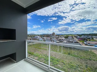 Vista panorâmica da área externa de um apartamento em Lajeado, mostrando a paisagem urbana e montanhas ao fundo.