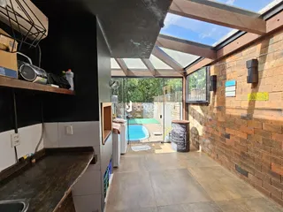 Vista interna de uma área com teto abobadado e parede de tijolos voltada para uma área externa com piscina.