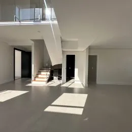 Vista interna de um espaço amplo com paredes brancas e teto de gesso.