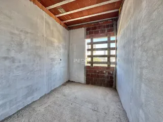 Interior de um cômodo com paredes brancas e teto de tijolos exposto.