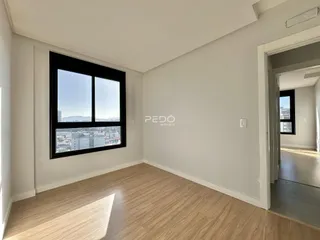 Sala de estar com piso de madeira e grande janela com vista para a cidade.