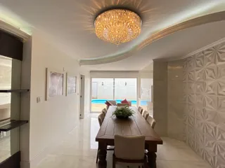 Sala de jantar com mesa de madeira e vista para a área externa com piscina.