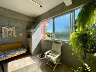Quarto com grande janela que oferece vista para a vegetação externa.