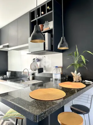 Foto de uma cozinha moderna com bancada escura e iluminação pendente.