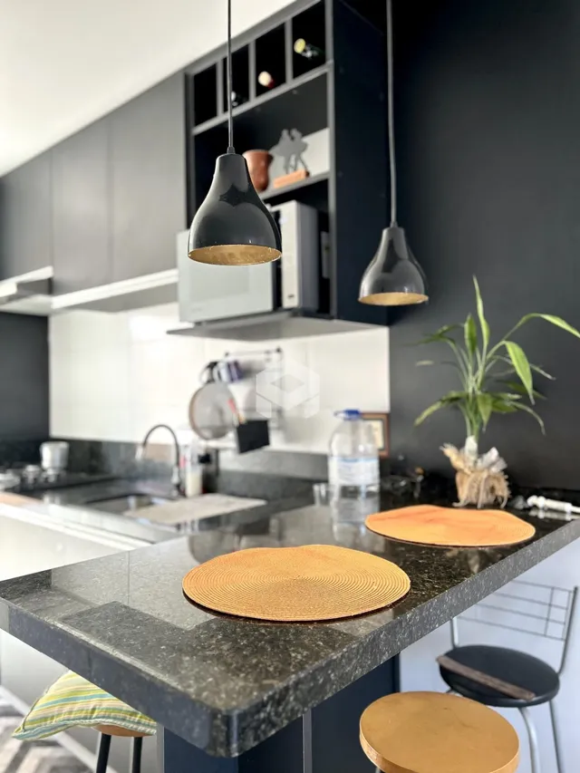 Foto de uma cozinha moderna com bancada escura e iluminação pendente.
