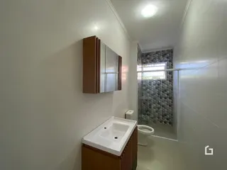 Foto de um banheiro com revestimento cerâmico e box de vidro.