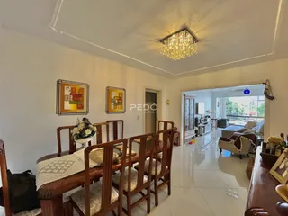 Uma sala de jantar com mesa de madeira e cadeiras em um imóvel no Brasil.