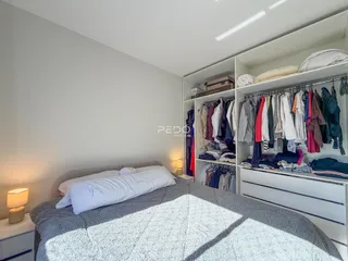 Quarto com cama e armários brancos.
