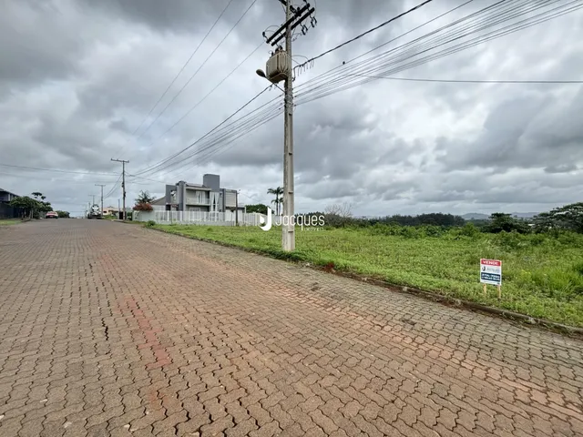 Vista da rua com uma residência e vegetação ao fundo.