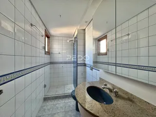 Foto de um banheiro com revestimento cerâmico branco e bancada de mármore.